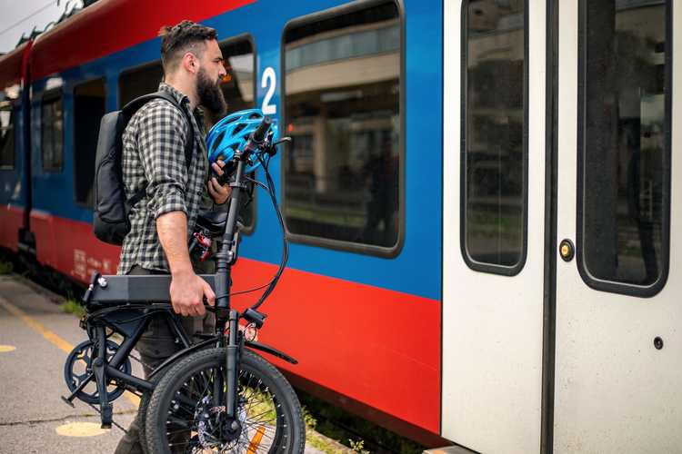 man with folding e-bike getting on train